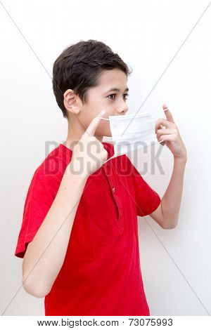  A sick young boy putting on a face mask to stop spread of germs.