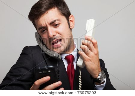 Stressed businessman talking on many phones at once