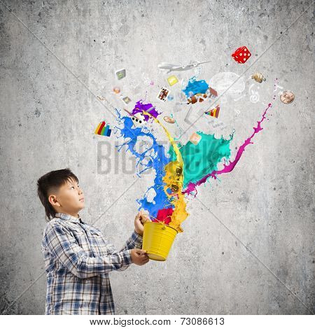 Young boy splashing colorful paint from bucket