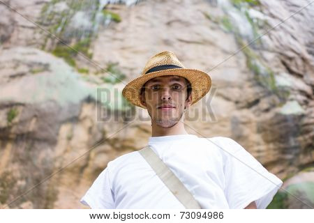 Young man enjoying in natural park at the base of large waterfall