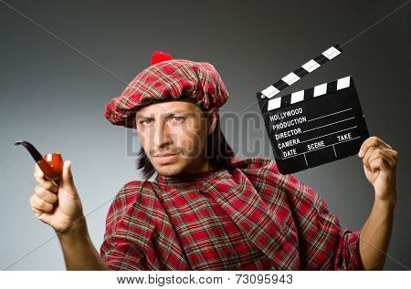 Funny scotsman with movie board and smoking pipe