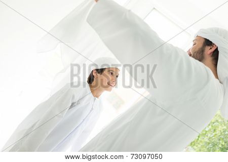 Happy Arabic father making headscarf to his son