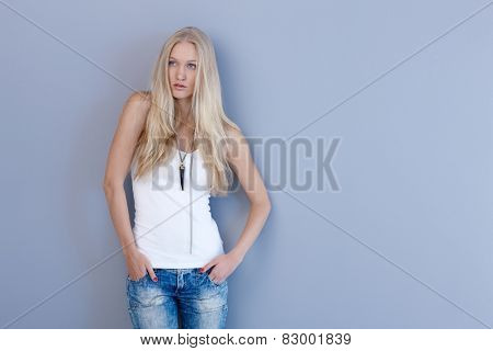 Casual nordic beauty in jeans and top posing by blue wall.