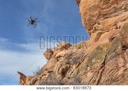 radio controlled hexacopter drone flying with a camera along sandstone canyon cliff