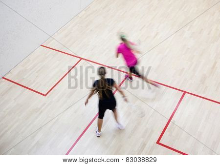 Two female squash players in fast action on a squash court (motion blurred image; color toned image)