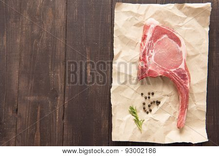 Top View Raw Pork Chop Steak On Paper On Wooden Background