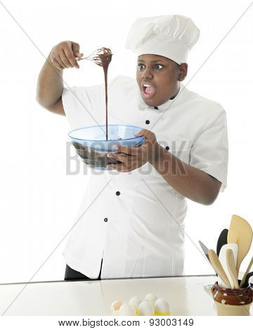 An African American chef shocked at the stream of chocolate batter that he's prepared.  On a white background.