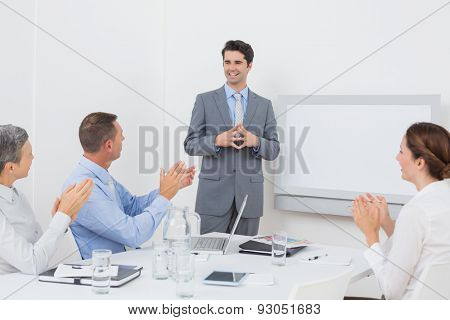 Business team applauding their colleague in the meeting room