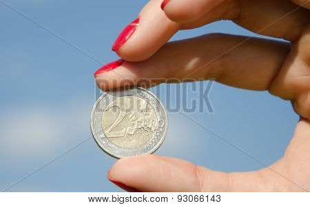 Coin euro in the hands against the sky