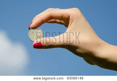 Coin euro in the hands against the sky