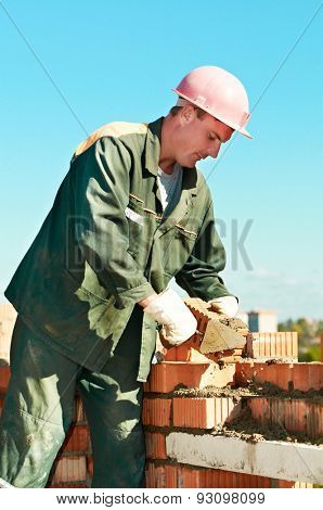 construction mason worker bricklayer making a brickwork with trowel and cement mortar