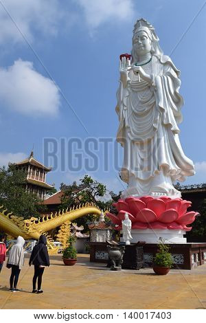 Binh Duong Vietnam June 16 2016: people praying at the big statue of Bodhisattva at Buddhist Chau Thoi temple
