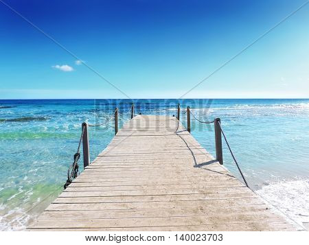 Boardwalk into the sea. Gangplank and turquoise colored water. Tropical sea scene.