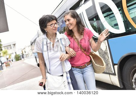 Senior woman with home carer getting off the bus