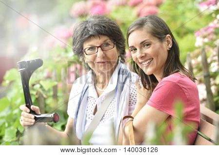 Senior woman with home carer sitting in park