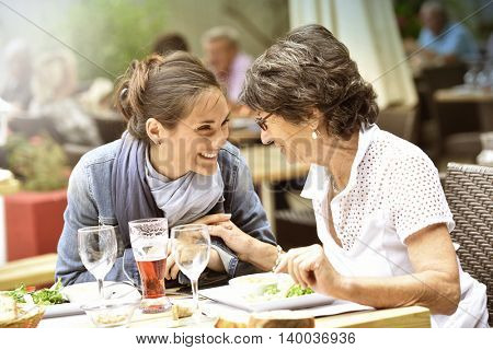 Senior woman with home carer having lunch at restaurant