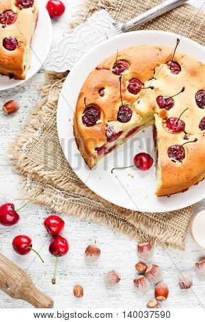 Cherry pie - delicious cake with cherry and nuts on white kitchen table with ingredients top view