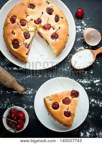 Cherry cake on a black background with the ingredients baking food background top view