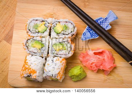 Sushi California rolls appetizer with rice avocado with chopsticks