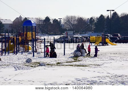 JOLIET, ILLINOIS / UNITED STATES - NOVEMBER 24, 2015: Children play in the snow, in the playground behind the Wesmere Elementary School, after a November snowstorm in Joliet.