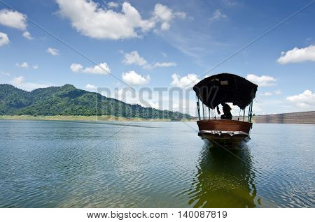 A fishing boat approaches shore area at Khun Dan dam Nakohn Nayok Thailand