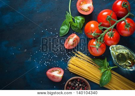 Ingredients for cooking Italian pasta - spaghetti tomatoes basil and oil. Top view with copyspace. Organic food.