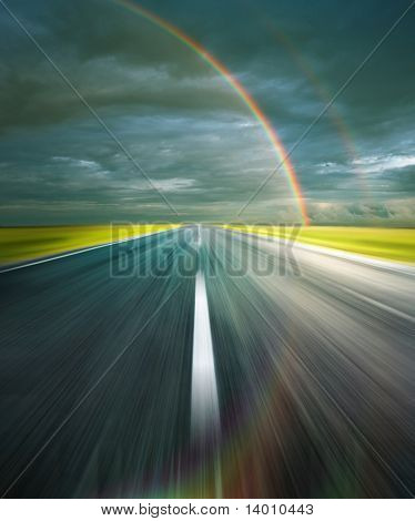 Nuages d'orage avec route arc-en-ciel et l'asphalte avec la réflexion de l'arc-en-ciel