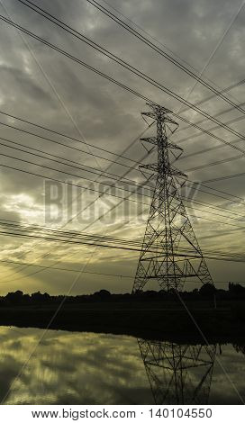 High voltage pylons on the rice field in the evening at sunset .