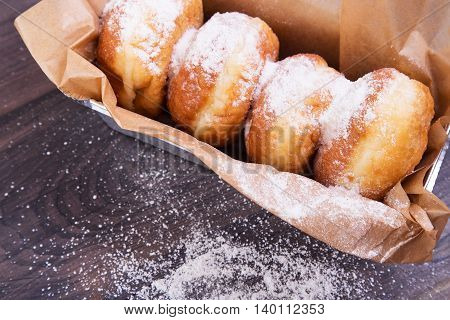 German donuts - delicious berliner with jam and icing sugar in a box on a dark wooden background. Space for text