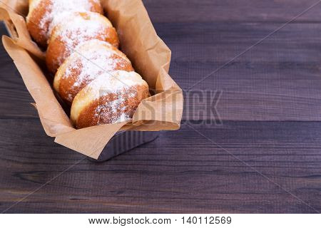 German donuts - delicious berliner with jam and icing sugar in a box on a dark wooden table. Space for text