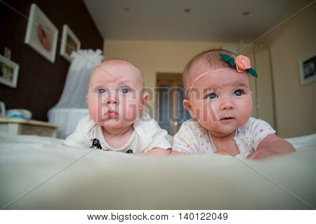 twin baby boy and girl lie on the bed in bedroom