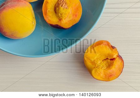Ripe peaches in blue bowl on white wooden background. Group of fresh peaches on white table. Juicy and fresh peach with place for text. Concept for healthy eating and nutrition. Top view. Copy Space.