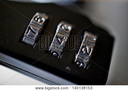 Macro detail of a black numerical combination lock with a silver number dial