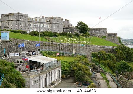 PLYMOUTH, UK - JULY 4: Tourists sit in an outdoor cafe and walk along the public promenade in the British south coast seaport city of Plymouth, Devon on July 4, 2016.