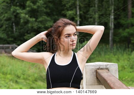The girl has risen to take rest after run in park.