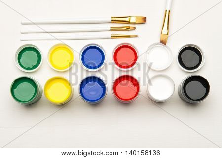 Color tempera water based paints with paintbrush on a white background