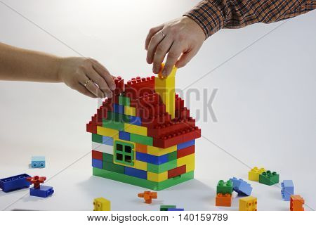 Toy house built by family - husband and wife. Their hands have rings. The symbol of building relationships