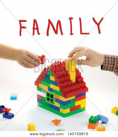 Toy house built by family - husband and wife. Their hands have rings. The symbol of building relationships
