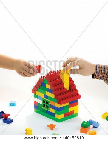 Toy house built by family - husband and wife. Their hands have rings. The symbol of building relationships