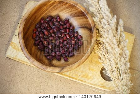 Dry briar in wooden plate. Dried rose hips and fluffy grass. Healthy resehip for brew.