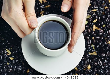 Hrnek s kávou v ruce nad kávová zrna pozadí
