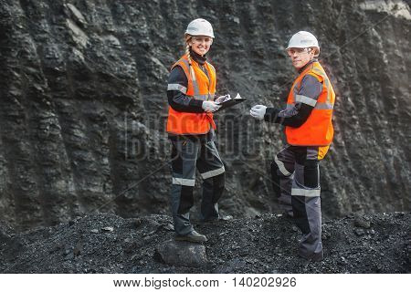 Two speacialists examining coal at an open pit