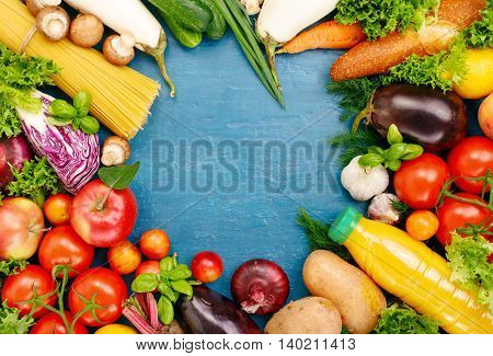 Frame of colorful fruits vegetables pasta and orange juice on blue surface. Frame of colorful fruits and vegetables background top view.