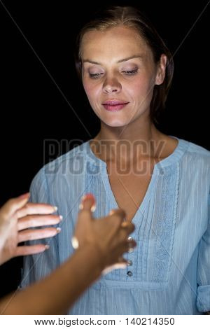 Cropped image of hypnotist hypnotizing woman against black background