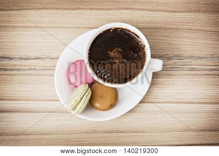 Cup of black coffee with tasty french colorful macarons. Sweet delight. View from above. Close up.