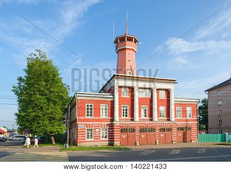 UGLICH RUSSIA - JULY 19 2016: Unknown people walk down street near building of fire department with watchtower. Building was built in years 1809-1811 on standard project. Project author Luigi Rusca