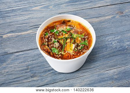 Japanese cuisine hot food delivery - miso soup at blue wooden background in white plastic plate
