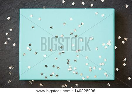 rectangular light blue box on black background with silver stars decorations. Holiday greetings. Engagement. turquoise on black board.