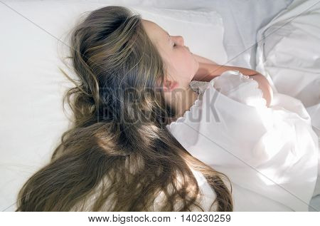 little girl is sleeping and her long hair spreads on pillow