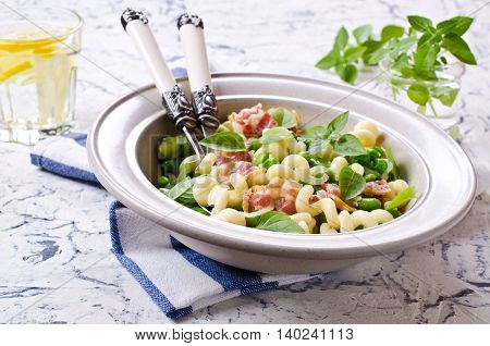 Pasta with bacon and vegetables in portion plate. Selective focus.
